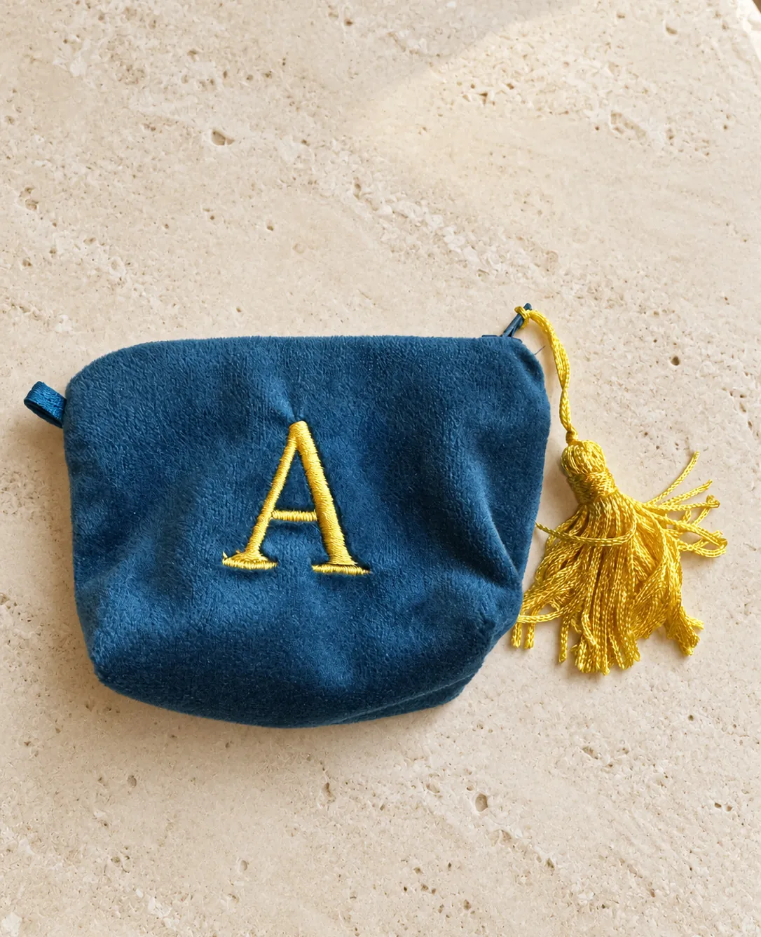 A mini velvet pouch with an embroidered initial